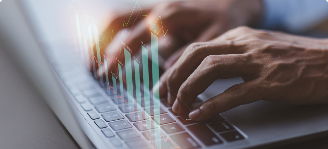 Photo of a pair of hands typing on a keyboard with graphs superimposed on the image 